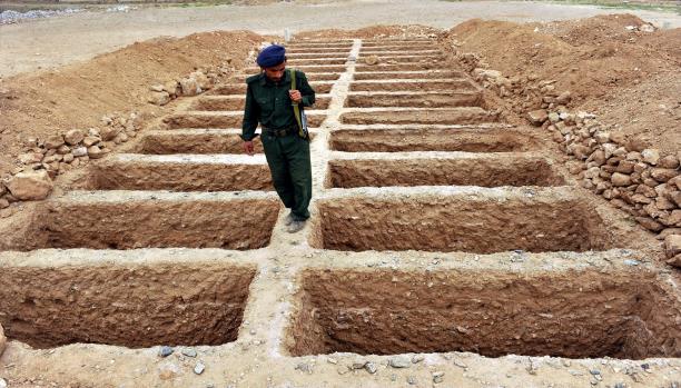 جندي يمني وسط قبور لدفن ضحايا المعارك