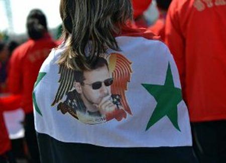 بالصورة... مسئولة سورية تضع صورة الأسد على علم سوريا بالأولمبياد