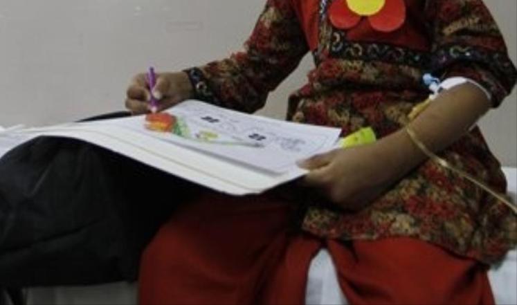 طفلة باكستانية مصابة بالتلاسيميا تلون في دفتر رسم أثناء جلسة نقل