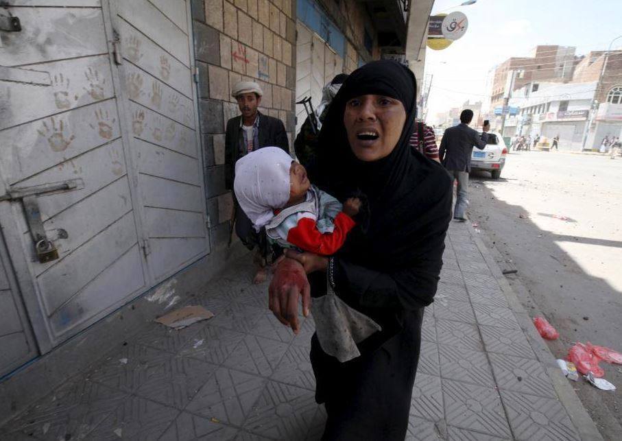 سيدة يمنية جريحة تحمل طلفتها وتجري في الشارع هرباً من انفجارات ج